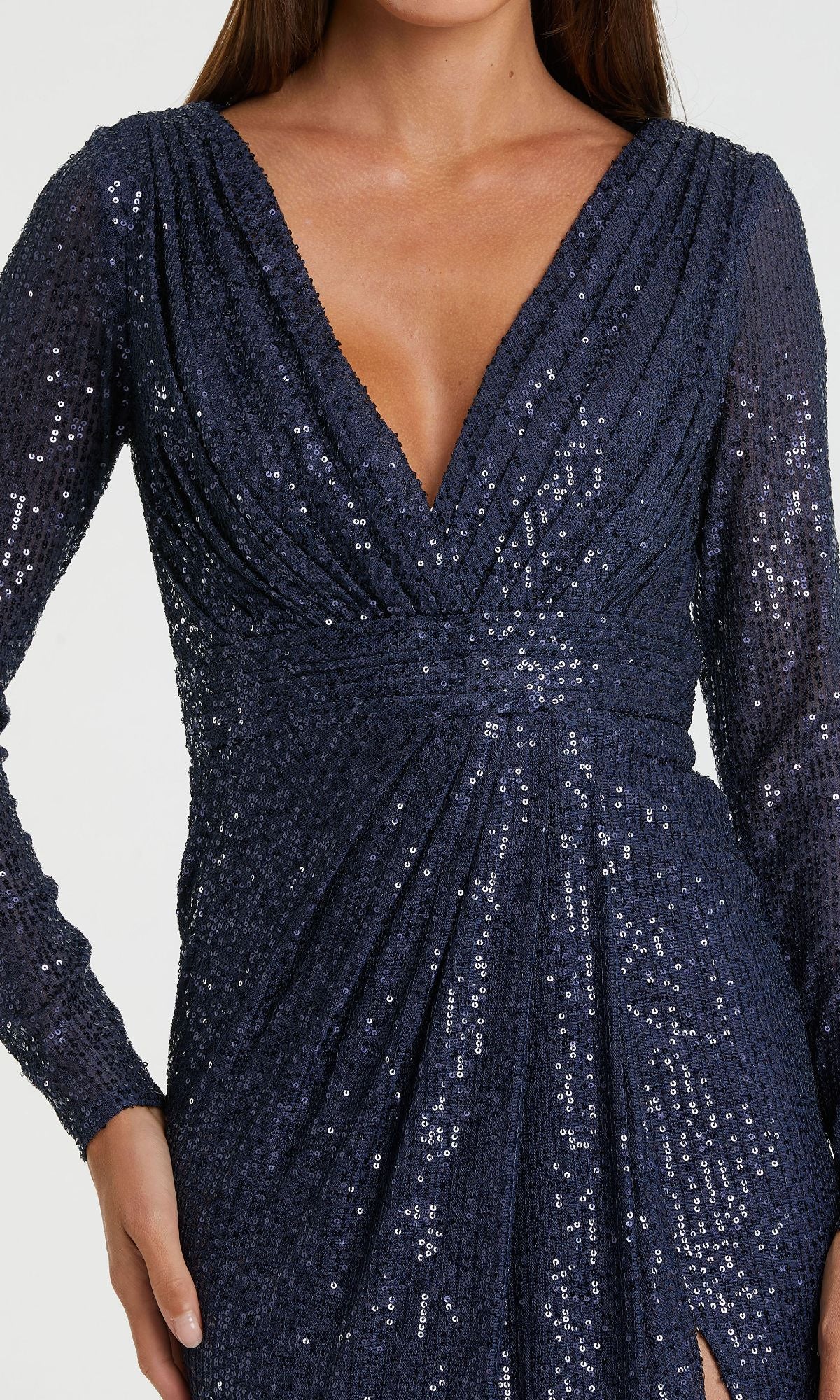 A person wearing the Mac Duggal 26490 Long-Sleeve Long Formal Dress in navy blue, featuring sequins throughout, a deep V-neckline, and gathered waist detailing.