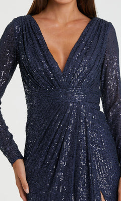 A person wearing the Mac Duggal 26490 Long-Sleeve Long Formal Dress in navy blue, featuring sequins throughout, a deep V-neckline, and gathered waist detailing.