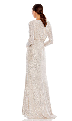 A woman faces away in the Mac Duggal 26490 Long-Sleeve Long Formal Dress, showcasing a fitted waist and sparkling silver sequins. Her hair is styled in a low ponytail.