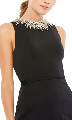 A woman models the Long Formal Dress 26516 by Mac Duggal—a sleeveless black dress with a fitted waist and pearl-embellished high neckline, adding elegance to the classic formal look.