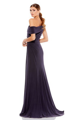 A woman in a dark purple Mac Duggal 26517 one-shoulder long prom dress stands turned slightly to the side, gazing over her shoulder with her hair styled in a low ponytail.
