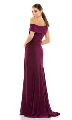 A woman stands facing away against a white backdrop, glancing over her shoulder in a floor-length magenta Mac Duggal 26517 one-shoulder long prom dress.