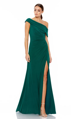A woman models the Mac Duggal 26517, a floor-length emerald green one-shoulder prom dress with a thigh-high slit, standing against a plain white background.