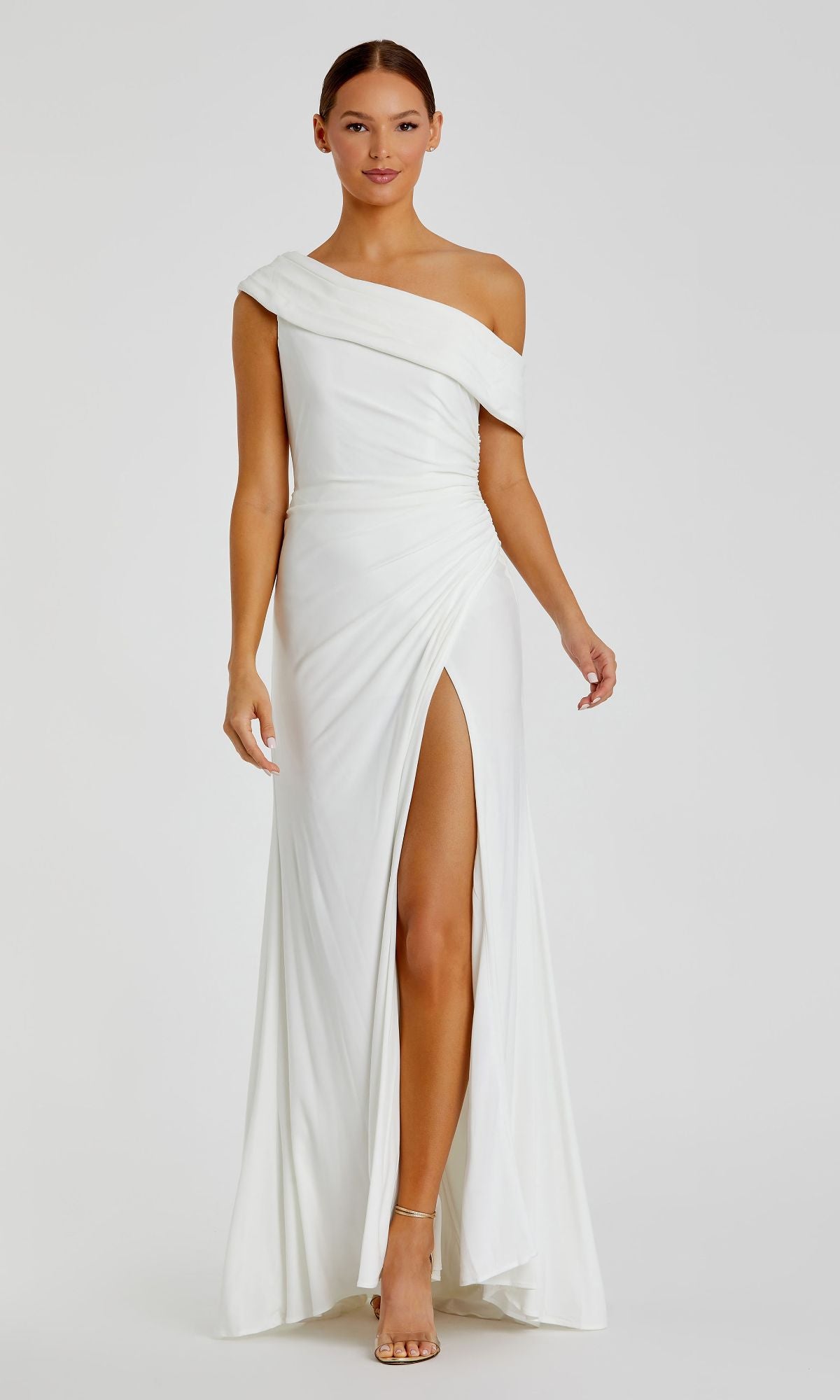Woman models the Mac Duggal 26517, a white, one-shoulder long prom dress with a floor-length silhouette and thigh-high slit, standing against a plain background.