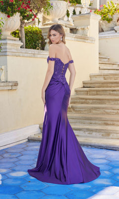 A woman wearing the Juliet JT2651K long purple off-the-shoulder prom dress stands outdoors on blue tiles near stone steps, looking over her shoulder.