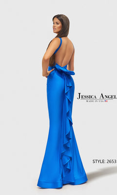 A woman wears the Jessica Angel 2653 long prom dress, featuring a backless royal blue mermaid style with a large bow and ruffle detail down the back.