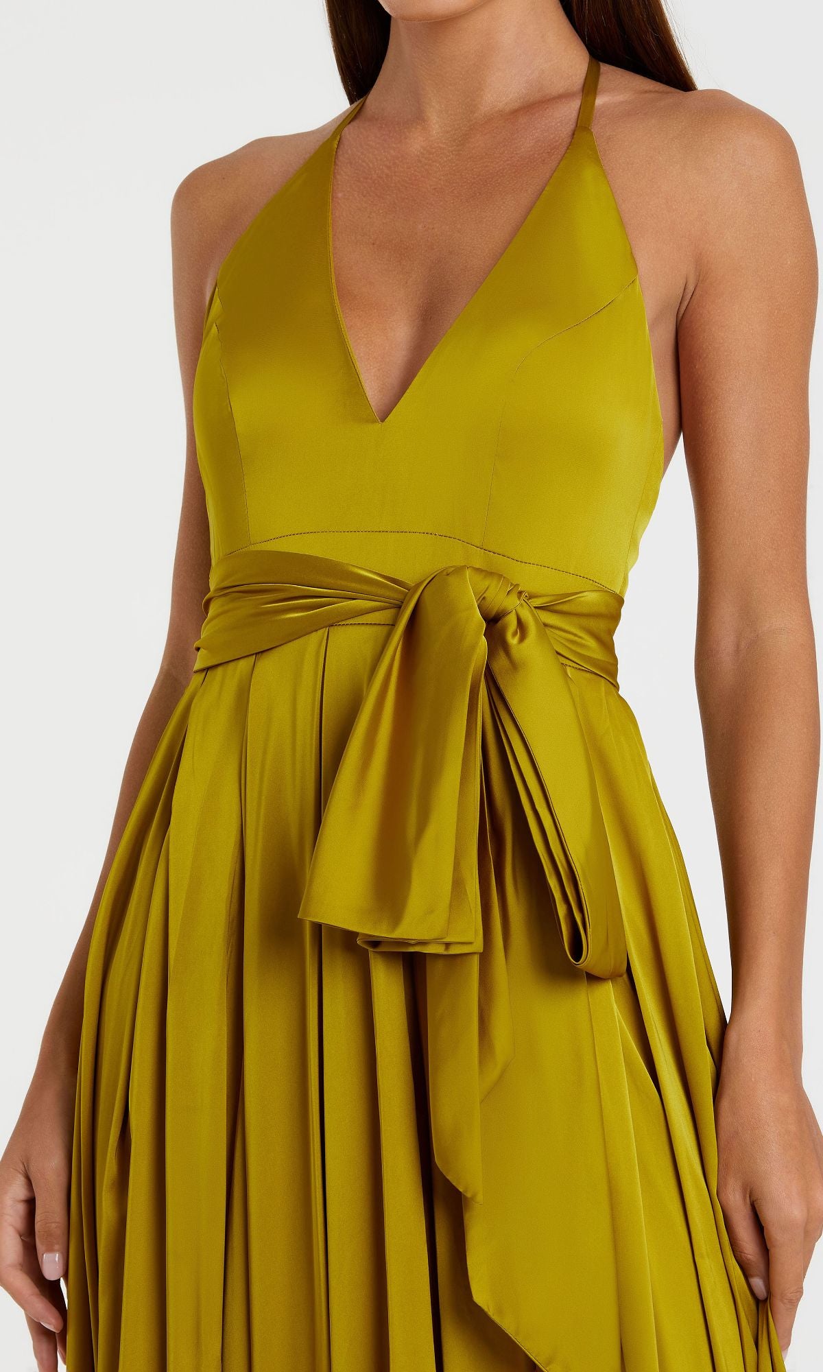 A woman wearing the Mac Duggal 26531 Bowed Long Halter Formal Dress in olive green satin, featuring a sleeveless design, pleated skirt, and wide sash tied in a bow at the waist.