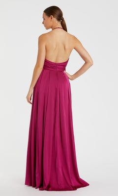 A woman stands with her back to the camera, wearing the Mac Duggal Bowed Long Halter Formal Dress (style 26531) in magenta, featuring a fitted bodice, backless halter design, and flowing floor-length skirt.