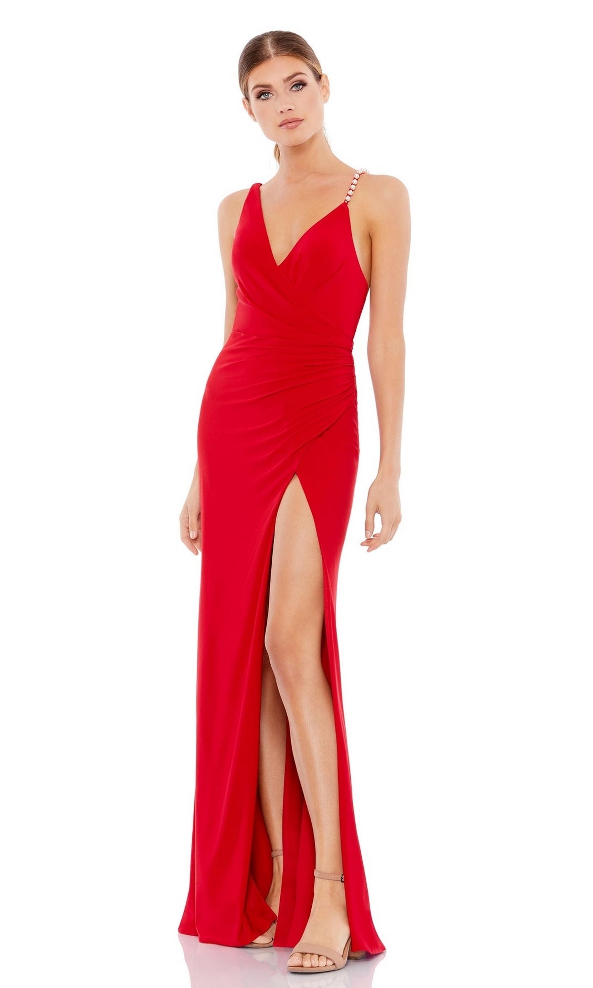 A woman stands in a neutral pose wearing the Mac Duggal Asymmetrical Red Formal Dress 265321, featuring a sleeveless V-neckline, beaded strap, and thigh-high slit.