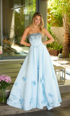 A woman stands outside in front of glass doors wearing the Ava Presley 26532 long prom dress, featuring a strapless satin design with a beaded bodice, sparkling details, and 3D floral appliques.