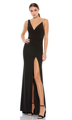 A woman in the Long Formal Dress 26532 by Mac Duggal, a sleek black gown with a V-neckline, beaded shoulder straps, thigh-high slit, and black high-heeled sandals.