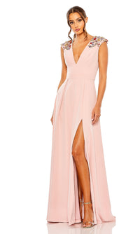 A woman wearing the Mac Duggal 26540 cap-sleeve long formal dress in light pink, featuring embroidered floral shoulders, a deep V-neckline, and a high front slit for an elegant evening look.