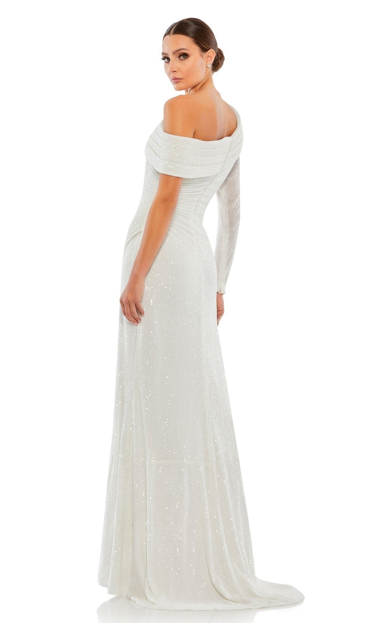A woman in the Mac Duggal 26571 one-sleeve white sequin formal dress stands looking over her shoulder, subtle sparkle catching the light against a plain white background.