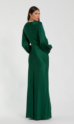 Woman wearing the Mac Duggal 26575 Long Sleeve Long Formal Dress in green satin stands facing away, glancing over her shoulder against a plain white background.