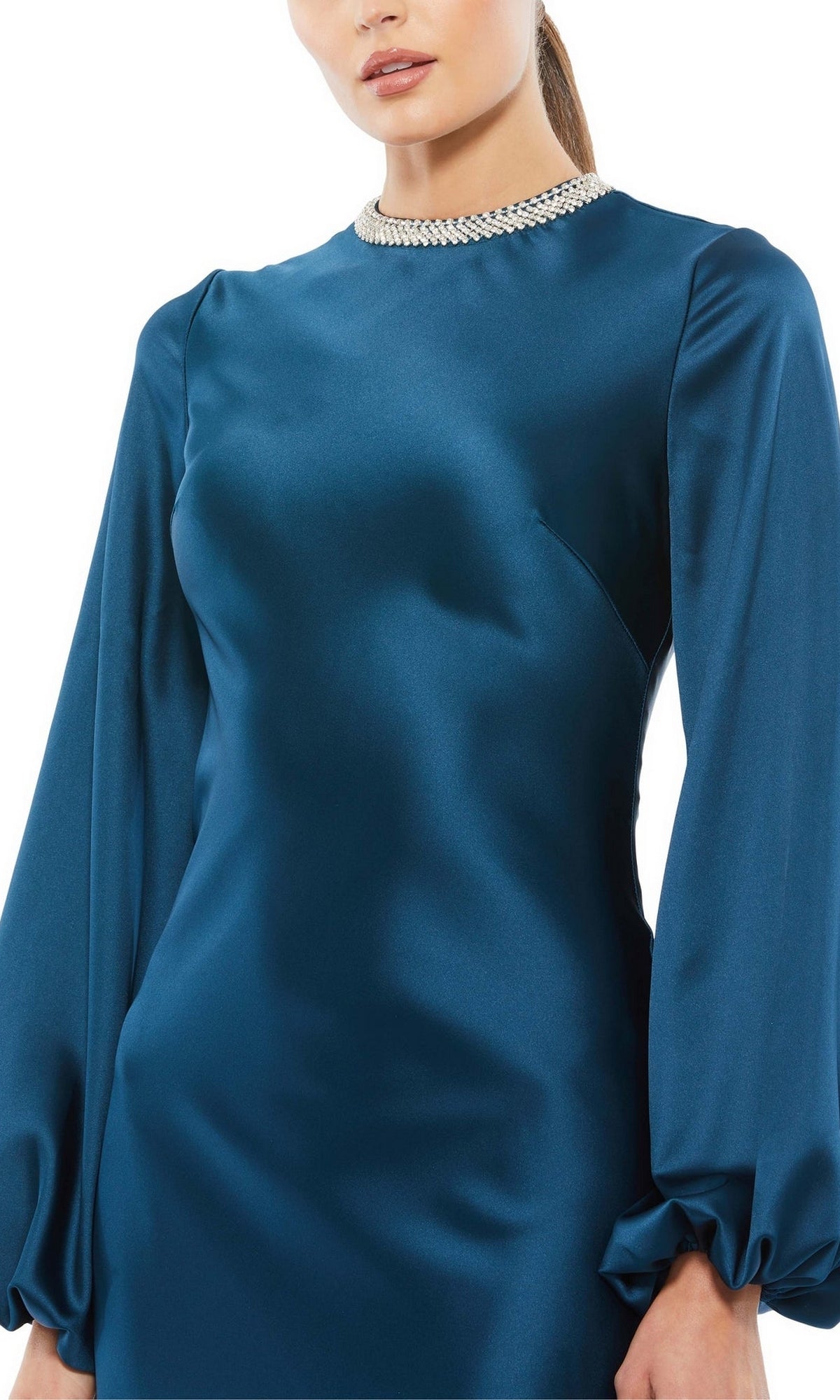 A woman wears the Mac Duggal 26575 long-sleeve formal dress in teal satin, featuring a high neckline with silver beaded trim for an elegant, modest evening gown look.