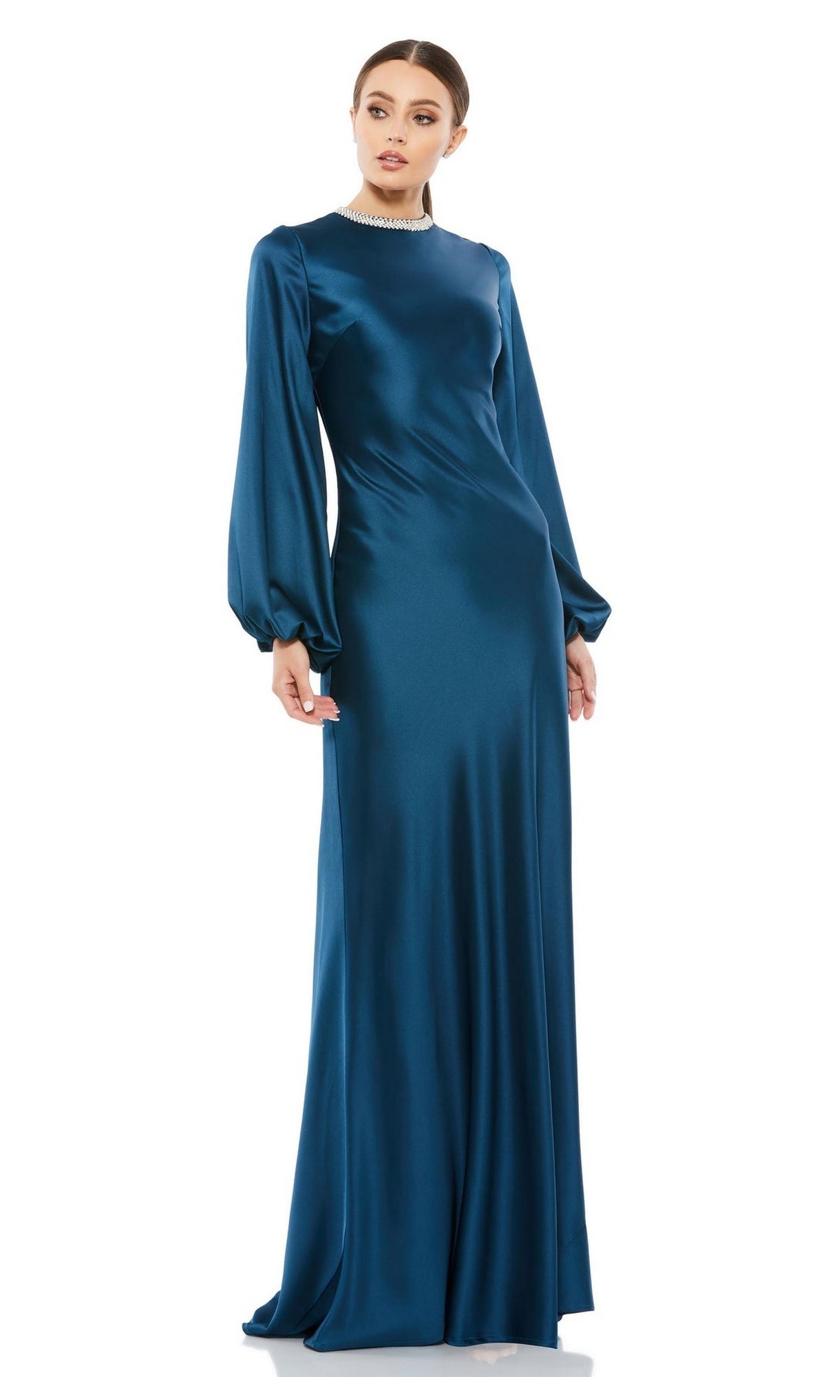 A woman stands against a white background wearing the Mac Duggal 26575: a long sleeve, floor-length teal satin formal dress with a high neckline and fitted silhouette.