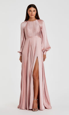 A woman models the Mac Duggal 26590, a light pink, long-sleeve pleated formal dress with a high slit and A-line silhouette, styled as an elegant evening gown against a plain white background.