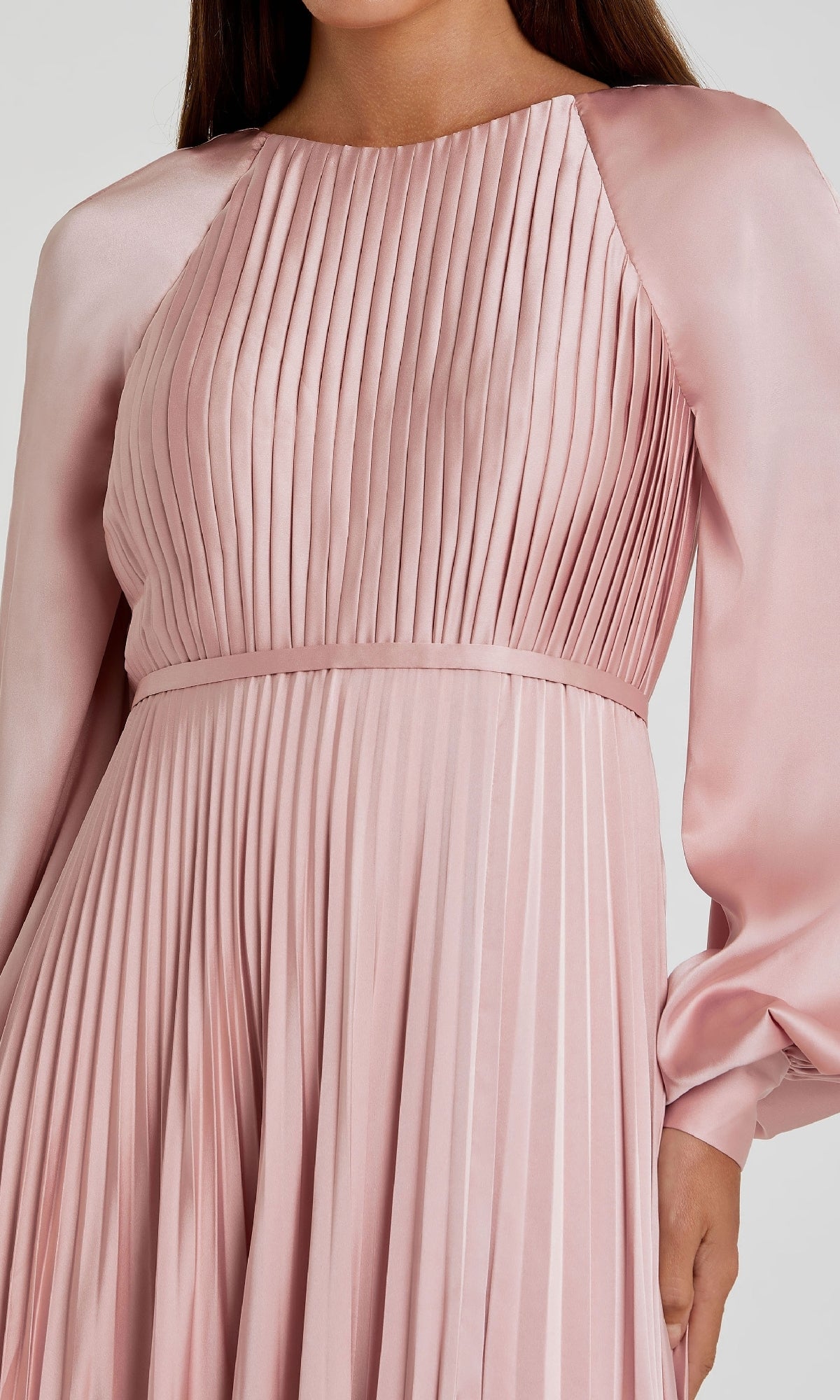 A woman wearing the Mac Duggal 26590, a long sleeve formal dress in light pink satin, featuring pleats, a fitted waist, and a high neckline.