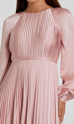 A woman wearing the Mac Duggal 26590, a long sleeve formal dress in light pink satin, featuring pleats, a fitted waist, and a high neckline.