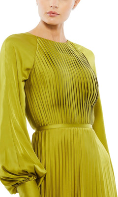 A person wearing the Mac Duggal 26590: a long-sleeved, olive green satin formal dress with pleats, a fitted waist, and round neckline.