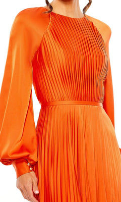 A person wearing the Mac Duggal 26590 long sleeve formal dress, a bright orange pleated gown with a fitted waist and buttoned cuffs.