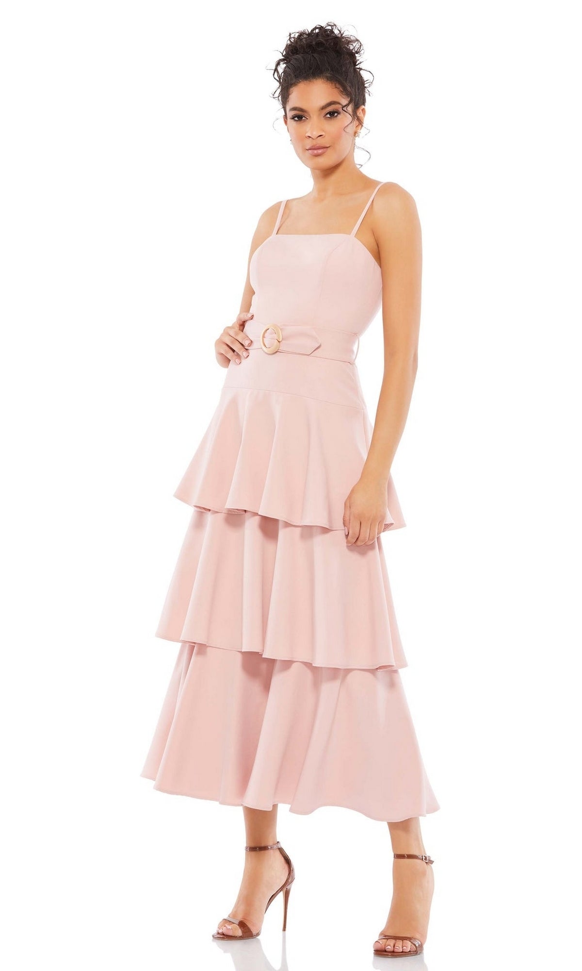 A woman in the Short Wedding Guest Dress 26629 by Mac Duggal—light pink, sleeveless, ruffle layered with thin straps and a belted waist—wears strappy high-heeled sandals against a white background.