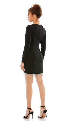A woman faces away, wearing the Short Homecoming Dress 26679 by Mac Duggal—a black, long-sleeve fitted dress with a beaded fringe hem—paired with black high-heeled sandals.