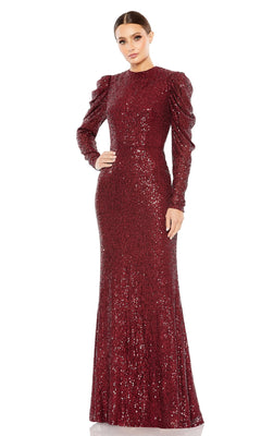 A woman stands against a plain white background wearing the Mac Duggal 26692 Long-Sleeve Sequin Formal Dress with structured shoulders and a floor-length silhouette.