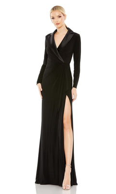 A woman wears the Long Formal Dress 26731 by Mac Duggal—a black, floor-length gown with a blazer-style top, long sleeves, one high slit—paired with silver high-heeled sandals.