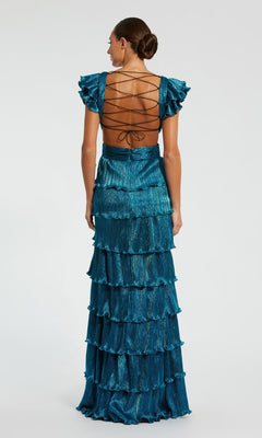 A woman faces away from the camera in a teal Mac Duggal Open-Back Tiered Formal Dress 26740, featuring ruffles, a floor-length v-neck design, and an elegant lace-up open back, set against a plain background.