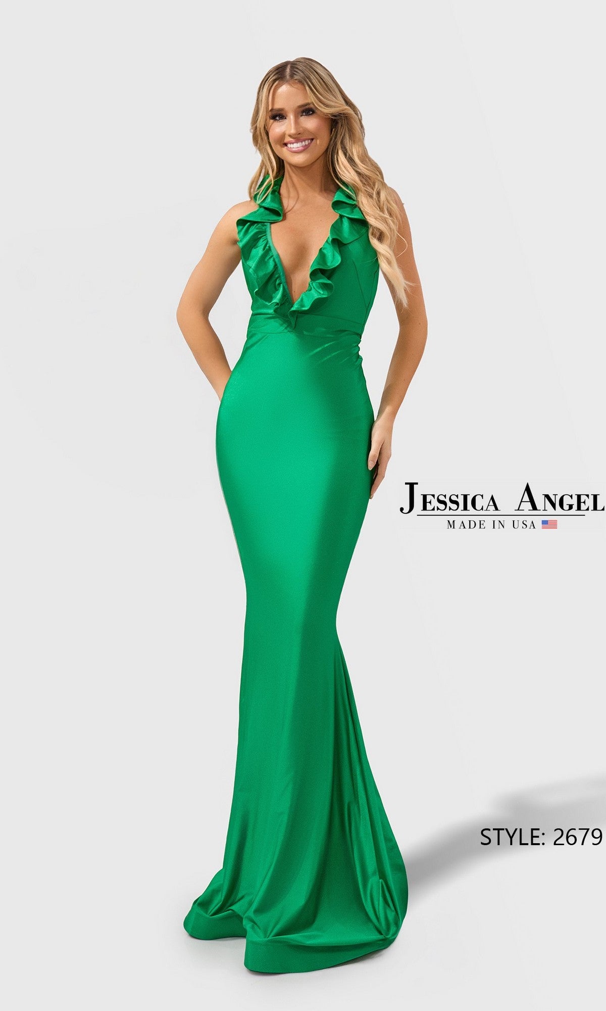 A woman smiles against a plain background wearing the Jessica Angel 2679 Long Prom Dress in Kelly, a sleeveless, floor-length gown with a deep V-neckline and ruffle accents.