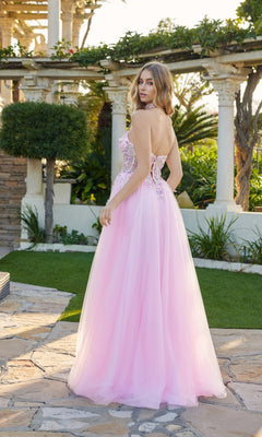 A woman stands outdoors on a stone path, facing away from the camera, wearing the Long Prom Dress: Juliet JT2682A featuring a strapless glitter design with a floral embroidered corset and tulle skirt.