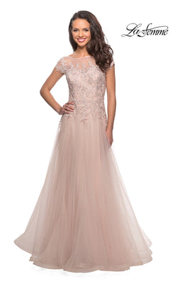 A woman stands smiling against a white background, wearing the Long Formal Dress: La Femme 26893 in light blush—a floor-length gown with a lace-embroidered bodice and cap sleeves.