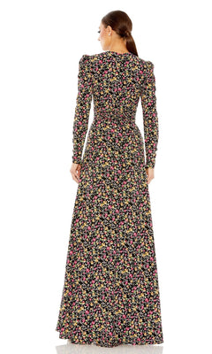 A woman faces away, wearing the Long Formal Dress 26916 by Mac Duggal—a floor-length black gown with long sleeves and a vibrant floral pattern.