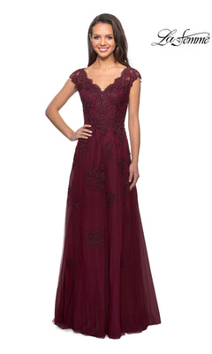 A woman stands wearing the La Femme 26942, a stunning, floor-length formal dress in burgundy with floral lace, cap sleeves, and beaded embellishments—an elegant choice for a mother-of-the-bride dress. The La Femme logo appears in the upper right corner.