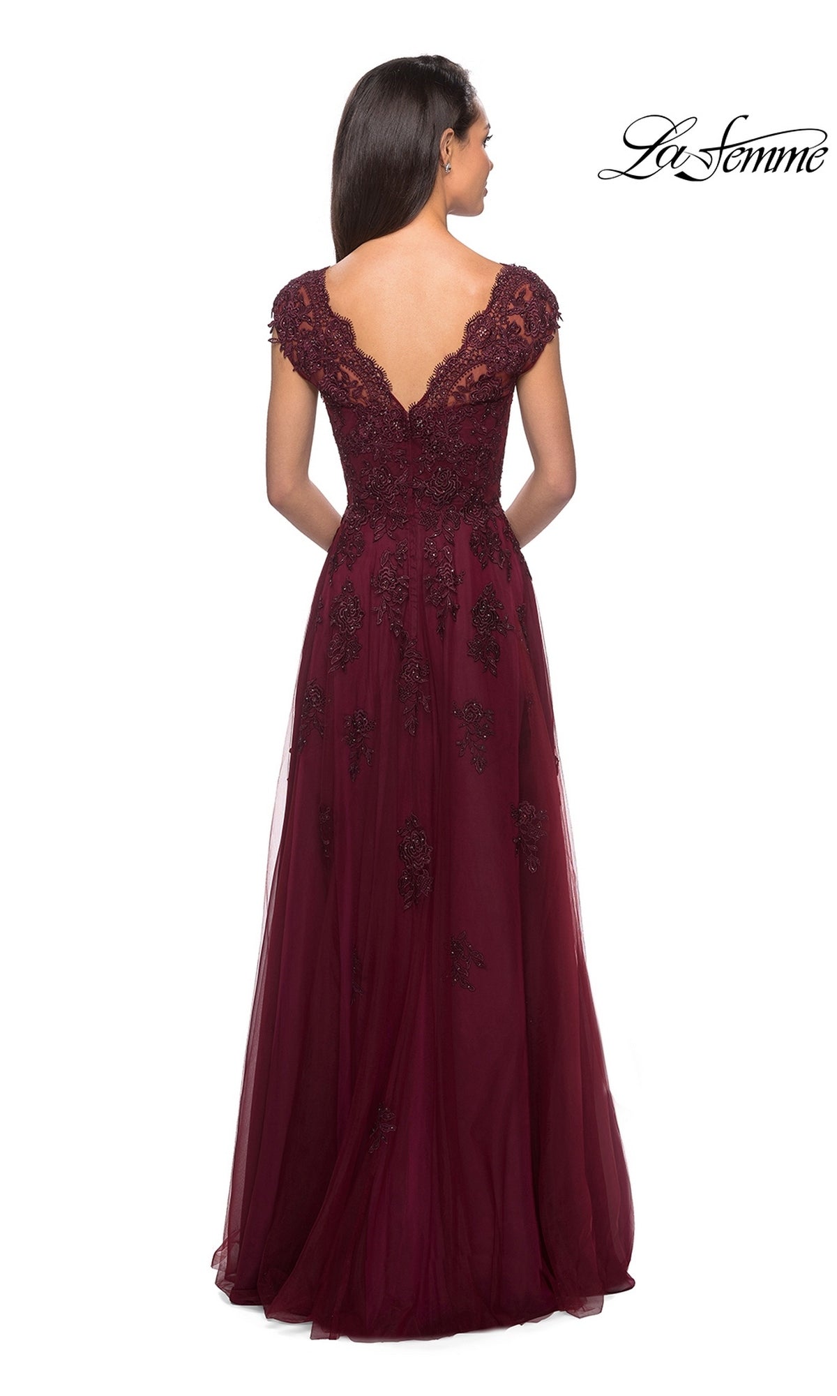 Wearing the La Femme 26942, a floor-length burgundy floral lace dress with cap sleeves and a deep V-back, this woman stands with her back to the camera—a sophisticated choice for a formal occasion or as a mother-of-the-bride dress.