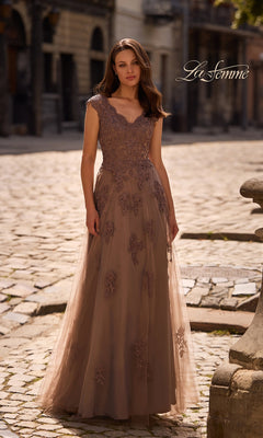 A woman wearing the Cocoa La Femme 26942 long formal dress stands on a cobblestone street with old buildings in the background.