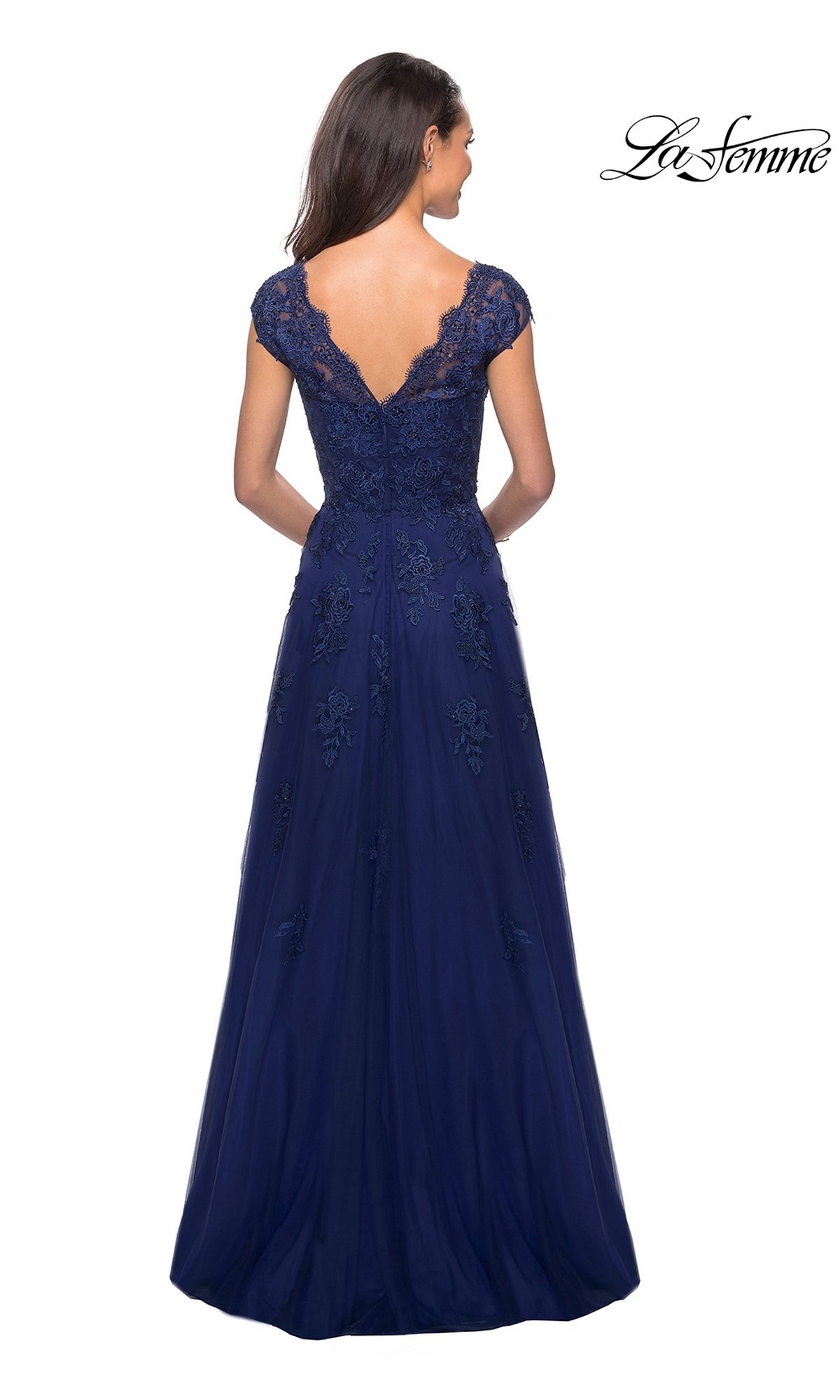 A woman is seen from behind, showcasing the La Femme 26942 long formal dress—a floor-length, navy blue gown crafted from floral lace with cap sleeves and a deep V-back. The elegant mother-of-the-bride dress features intricate floral embroidery and a flowing skirt. The “La Femme” logo appears in the top right corner.