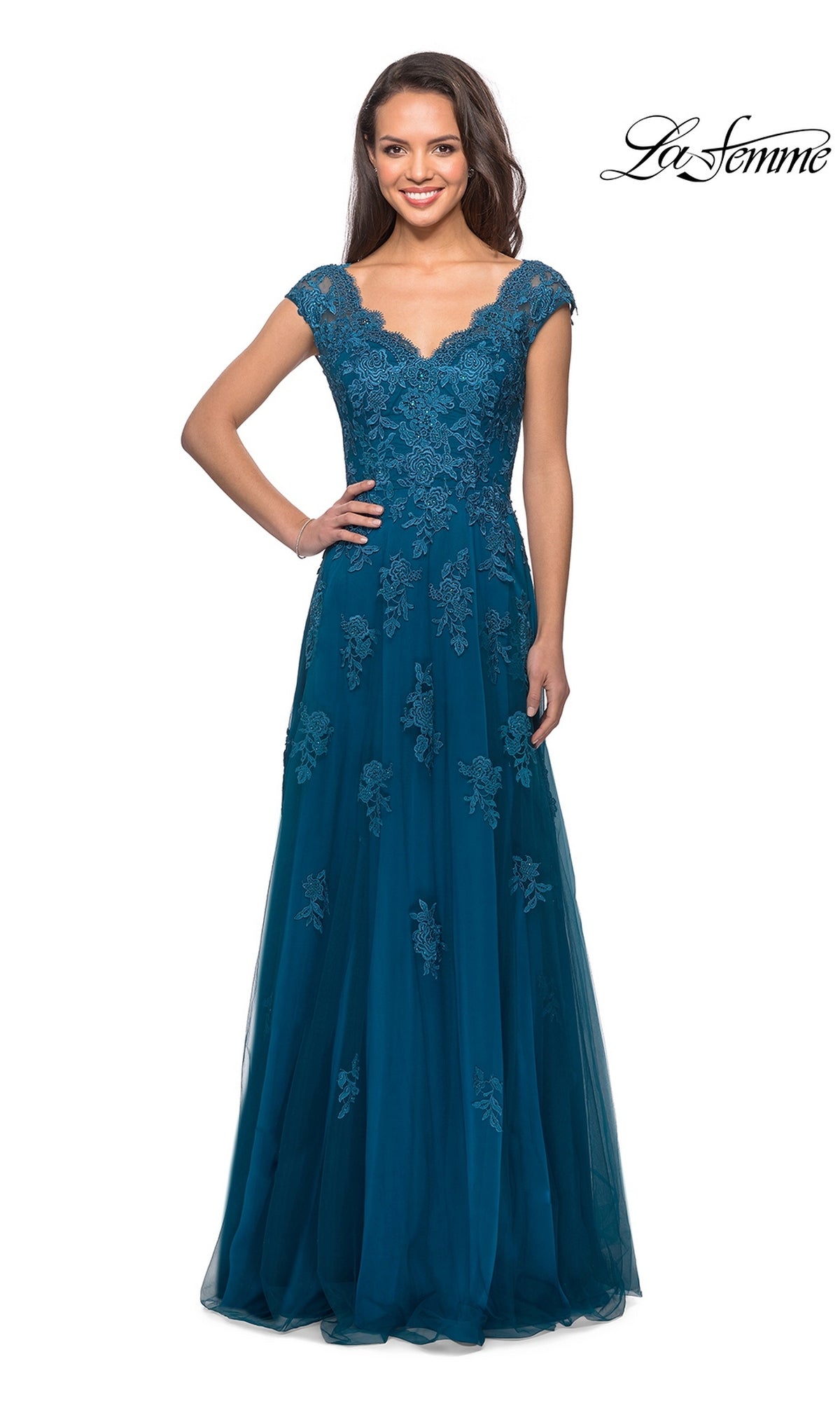 A woman wears the Long Formal Dress: La Femme 26942 in teal, featuring floor-length floral lace with delicate appliqué, cap sleeves, and a fitted bodice. Perfect as a mother-of-the-bride dress or for any formal event, she stands smiling against a white background with the “La Femme” logo visible in the corner.