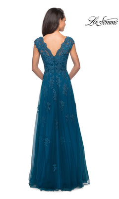 A woman stands facing away from the camera, showcasing the La Femme 26942 long formal dress—a teal, floor-length gown featuring lace detailing and a deep V-back. The “La Femme” logo appears in the upper right corner.