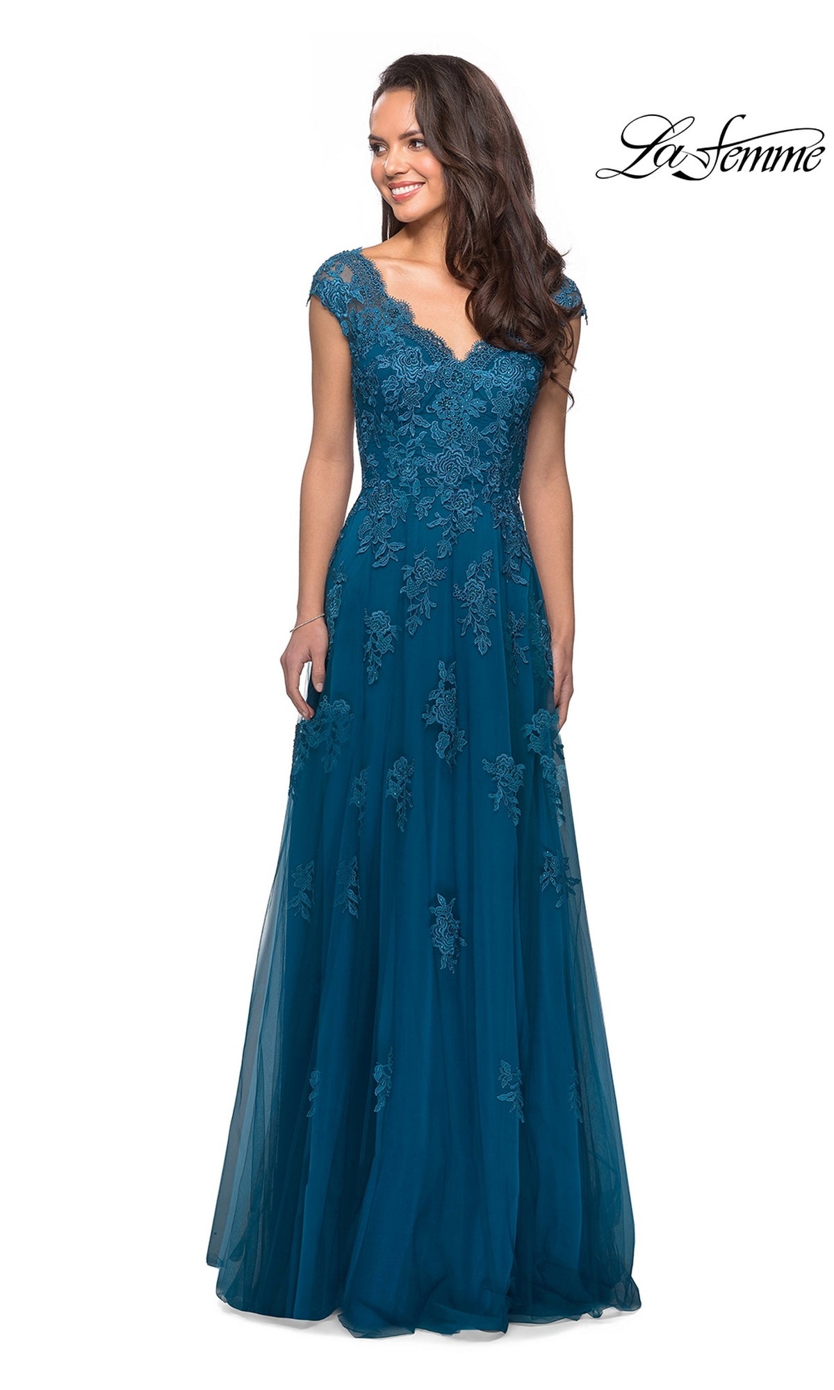 A woman is standing and smiling in the Long Formal Dress: La Femme 26942, a teal floor-length gown featuring lace floral detailing, cap sleeves, and a V-neckline. The La Femme logo appears in the top right corner.