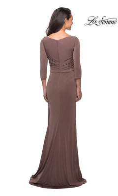 A woman is standing with her back to the camera, wearing the La Femme 26955 Long Formal Dress—a modest gown featuring three-quarter length sleeves and a fitted sheath skirt. The “La Femme” logo appears in the top right corner.