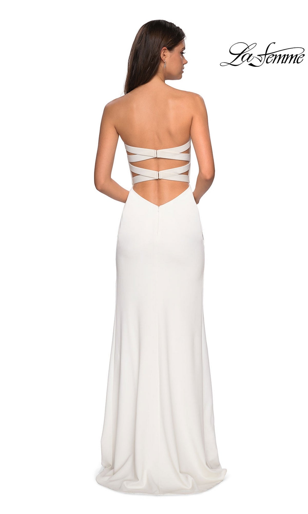 A woman in the La Femme Sleek Strapless Long Prom Dress 27035, featuring an open back and crisscross straps, stands facing away from the camera. 