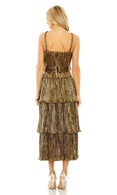 A woman faces away, wearing the Mac Duggal Tea-Length Metallic Party Dress 27062—a sleeveless, gold, tiered cocktail dress with a belted waist—paired with strappy high heels for a glamorous look.
