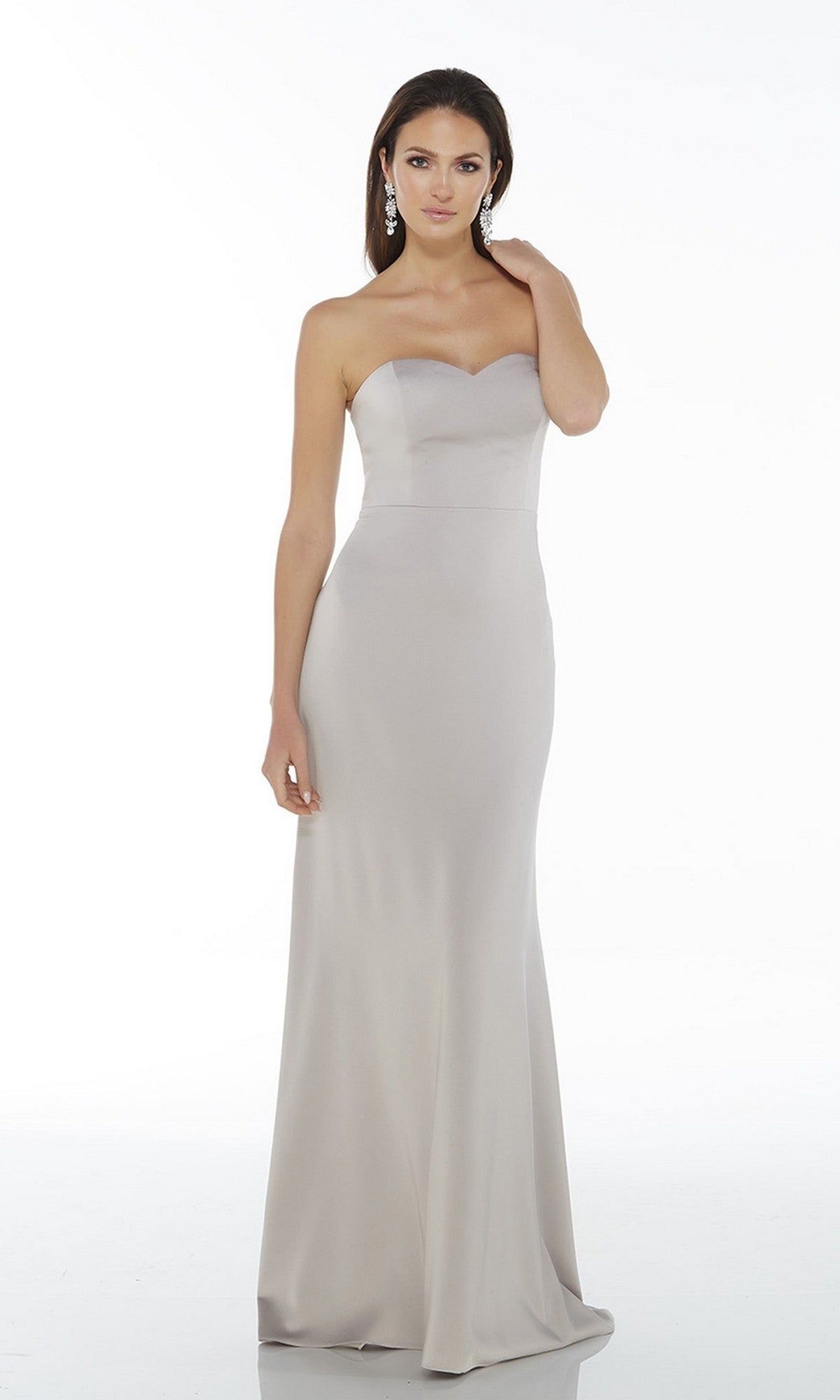 A woman wearing the Alyce 27105 long formal dress in silver stands against a plain white background.