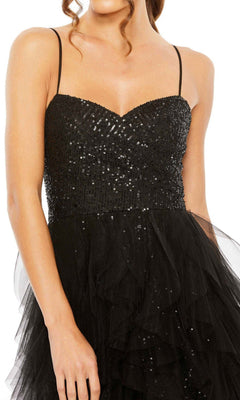 A woman wears the Mac Duggal 27119 Overskirt Mini Sequin Prom Dress, featuring thin straps and a layered tulle skirt—an elegant choice for any evening event.