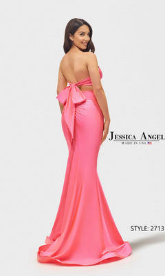 A woman models the Long Prom Dress: Jessica Angel 2713 in bright pink, striking a pose before a white background. The strapless gown stands out with its dramatic large back bow detail.