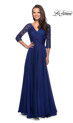 A woman wears the Long Formal Dress: La Femme 27153, a modest navy blue chiffon formal dress with a V-neckline and three-quarter length lace sleeves.