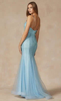 A woman in the Princess-Cut Long Glitter Mermaid Prom Dress 271, featuring thin straps and a light blue shimmer, stands against a beige backdrop, looking over her shoulder.