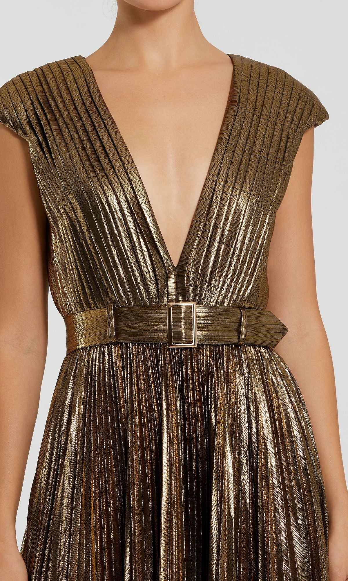 A person wearing the Pleated Long Bronze Evening Gown (Mac Duggal 27215) featuring metallic gold pleats, a deep V-neckline, and a matching belt for timeless elegance.